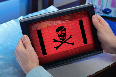 man with tablet at home watching your web page with a cyber attack / hands of a man consulting in touchscreen a hacked websiteの写真素材