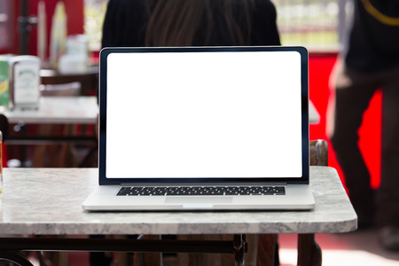 computer on the table with white screen in cafe bar / laptop with white screen on a table in a coffee shopの写真素材
