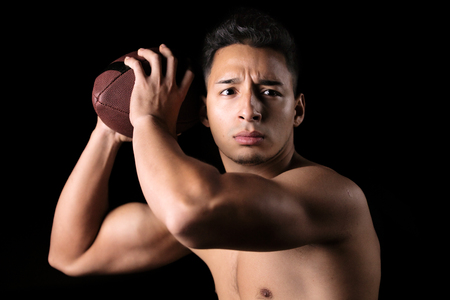 Portrait American football player with the ball in his hands ready to launch pass / Football player holding a ball in his handsの写真素材