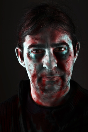 Halloween man with painted face on black background / portrait of scary bad zombie looking at camera for theme halloweenの写真素材