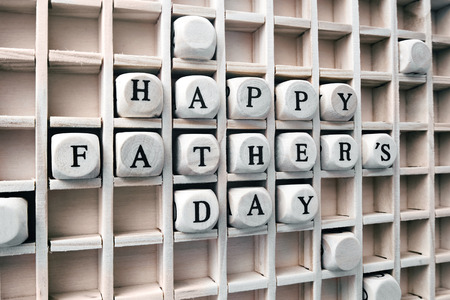 Composition of the words happy fathers days with wooden cubes in gameboard / Message happy fathers days made with building wooden blocks in square boxの写真素材
