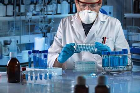 Technician working with biological samples in genetical lab / geneticist holding multi well plate...