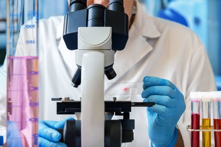 Biochemical Engineer analyzing a sample on the microscope slide / Microscopist working with...