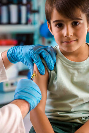 doctor administers one of the vaccines for covid-19 to the child population / Doctor injecting a vaccine to a child in the doctor's office