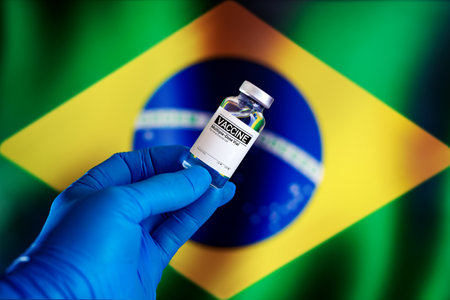 vial of vaccine for the vaccination plan against diseases in Brazil. Doctor with a vial with doses of the vaccine in front of the Brazilian flagの写真素材