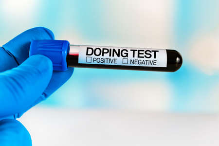 Tube of blood for analysis labeled Doping Test. Lab technician holding a blood sample tube for...