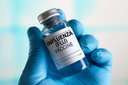 doctor with Influenza (Flu) or Grippe vaccine bottle for the annual flu disease prevention campaign. Influenza (Flu) Vaccine vialの写真素材