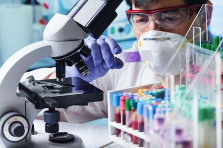 Research scientist working with biological blood samples of a patient in the hematology laboratory. Scientific microbiologist preparing blood smear for analysis under the microscopeの写真素材