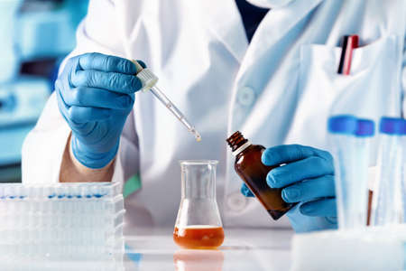 Work Chemist pipetting drop fluid of a bottle in the products research laboratory. Scientist...