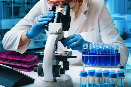 Scientist researcher analyzing molecular samples to microscope of laboratory. Microbiologist working...