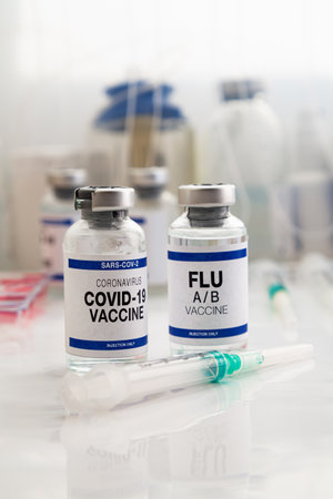 Coronavirus vaccine bottles and Flu Shot vaccine for booster vaccination for new variants of Sars-cov-2 virus and Influenza A. Flu A-B and Covid-19 vaccine vials for booster shot for omicron and Influenza virusの写真素材