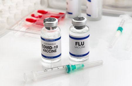 Coronavirus vaccine and Flu vials vaccine for booster vaccination for new variants of Sars-cov-2 virus and Influenza A. Flu and Covid-19 vaccine ampoules for booster shot for Influenza virus and covid omicronの写真素材