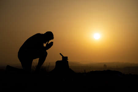 silhouette of person meditating at sunsetの写真素材