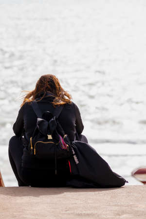 Sad and alone young woman sitting on the beach at sunset.の写真素材