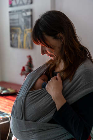 Young mother holding her newborn child. Mom nursing baby. Woman and new born boy relax in a white...