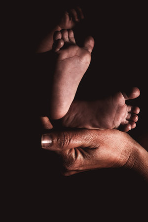 Baby feet held by loving mother in black and white.