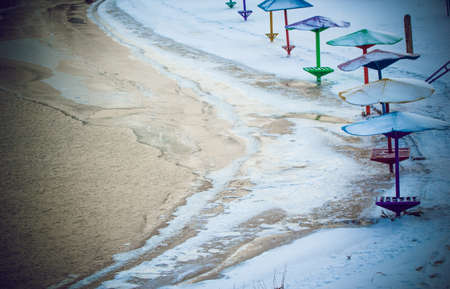Snow covered beach with frozen umbrellas. Winter landscape.の写真素材