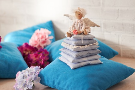 Little angel doll sitting on a pillow. Valentine's day. Children's toy hand madeの写真素材