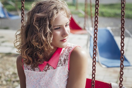 beautiful young blonde girl enjoying the summer in the Park of old rides and carousels.の写真素材