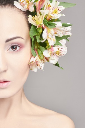 Beautiful Nude attractive brunette with flowers on his head. Fashion beautiful makeup, clean skin, facial care. Portrait of young beautiful woman with perfect skinの写真素材
