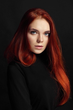 Sexy beautiful redhead girl with long hair. Perfect woman portrait on black background. Gorgeous hair and deep eyes. Natural beauty, clean skin, facial care and hair. Strong and thick hair. Flowerの写真素材