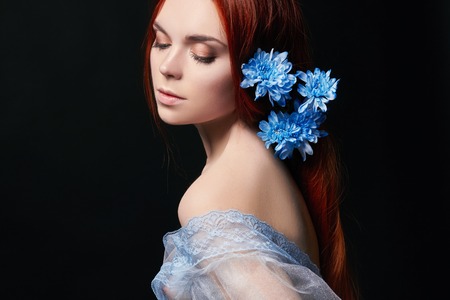 Sexy beautiful redhead girl with long hair in dress cotton retro. Woman portrait on black background. Deep eyes. Natural beauty, clean skin, facial care and hair. Strong and thick hair. Flowerの写真素材