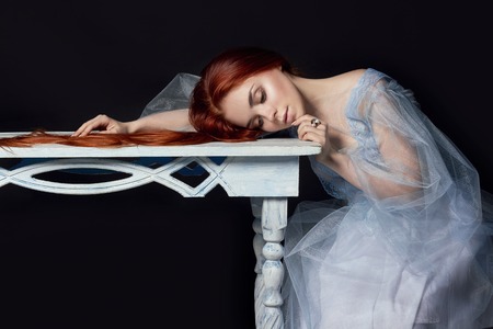 Sexy beautiful redhead girl with long hair. Perfect woman portrait on black background. Gorgeous hair and deep eyes. Natural beauty, clean skin, facial care and hair. Strong and thick hair. Wood tableの写真素材