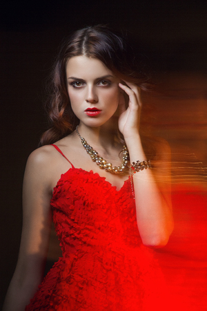 Blurred color art portrait of a girl on a dark background. Fashion woman with beautiful makeup and a light summer dress. Sensual tender image of a girl in motion. Studio portraitの写真素材