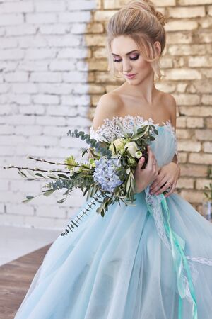 Bride in a beautiful turquoise dress in anticipation of wedding. Blonde in lace dress sea green with a bouquet . Happy bride, emotion, joy on his face. Beautiful makeup, manicures and hairstyles womenの写真素材