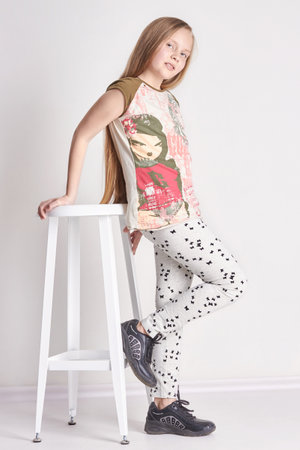 Russia Ekaterinburg - April 1, 2016: Young girl child with long hair sitting on a chair. Smile joy emotions on her face. Girl posing on light background. Summer lookのeditorial素材