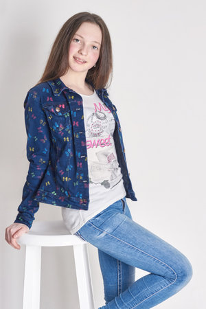 Russia Ekaterinburg - April 1, 2016: Young girl child sitting on a chair. Smile joy emotions on her face. Girl in jeans posing on light background. Summer lookのeditorial素材