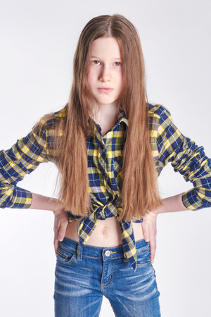 Russia Ekaterinburg - April 1, 2016: Fashion fun girl in shirt and jeans posing on a white background. Model school for children. Beautiful baby smilingのeditorial素材