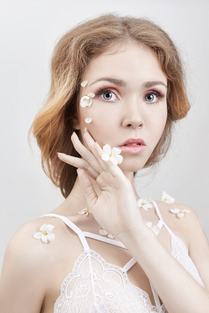 Art blond woman with flowers on the body in underwear white. Cosmetics for face and body, skin care, rejuvenation, wrinkles, eliminating age-related wrinkles. Naked girl in underwearの写真素材