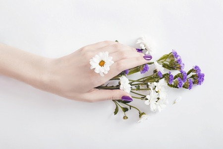 Fashion art portrait woman in summer dress and flowers in her hand with a bright contrasting makeup. Creative beauty photo girls sitting at table on a contrasting pink background with colored shadowsの写真素材