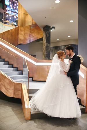 Bride and groom hugging and kissing while standing on the stairs. Wedding, gentle embrace of man and woman. The family, the husband and wifeの写真素材