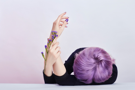 Summer girl with purple hair Beautiful well-groomed hands with wild flowers lying on the table, cosmetics for hands. Care and beauty for skin, moisturizing skin and Spa, contrasting makeupの写真素材