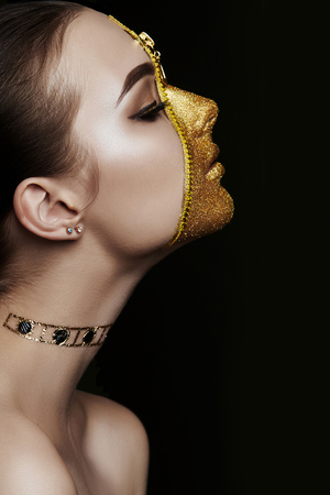 Creative grim makeup face of girl Golden color zipper clothing on skin. Fashion beauty creative cosmetics and skin care halloween. Brunette woman on dark background, beautiful big eyes and smooth skinの写真素材