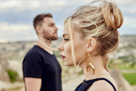 In love Eastern couple in mountains of Cappadocia hugs and kisses. Love and emotions loving couple vacationing in Turkey. Closeup portrait man and woman. Beautiful Crescent moon earrings on girl earsの写真素材
