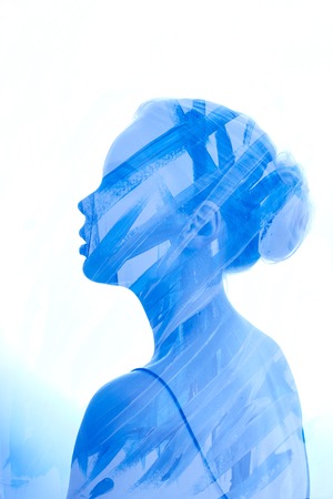 Art Portrait woman consisting of brush strokes of blue paint on a white background. Paint on girl face, fashion beauty and makeup. Double exposure, no focus. The mysterious portrait streaks blue paintの写真素材