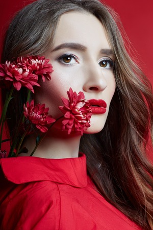 Woman with curly hair in red dress and flower hand