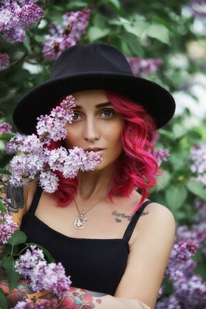 Fashion girl with red hair and big round hat, spring portrait in lilac colors in summer. Beautiful...