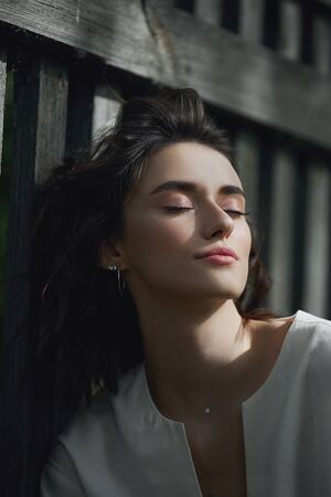 Portrait of a blonde girl walking in the Park in nature. Outdoor fashion beautiful young woman surrounded by lilac flowers in summer. Spring blooms lilac Bushの写真素材