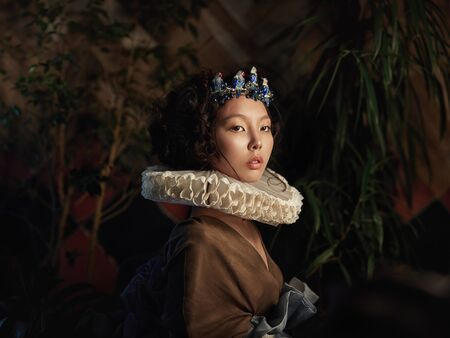 Art portrait of a girl Princess Queen in foliage and greenery, fabulous romantic image of an Asian...