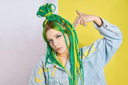 Portrait of a woman with creatively colored hair in green and yellow color. Colorful bright dreadlocks, beautiful modern makeupの写真素材