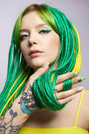 Portrait of a woman with creatively colored hair in green and yellow color. Colorful bright dreadlocks, beautiful modern makeupの写真素材