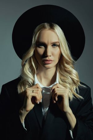 Portrait of a Blonde woman in a big round black hat, hair stylingの写真素材