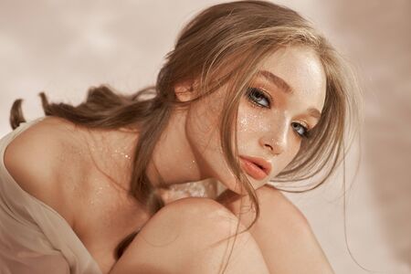 Beautiful sexy woman sitting on the floor, cosmetics and makeup on the girl face and bodyの写真素材