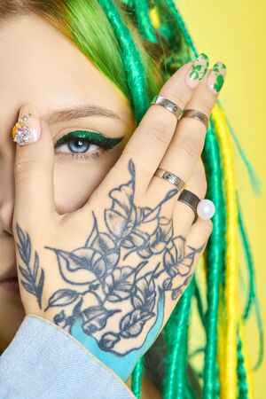 Portrait of a woman with creatively colored hair in green and yellow color. Colorful bright dreadlocks, beautiful modern makeupの写真素材