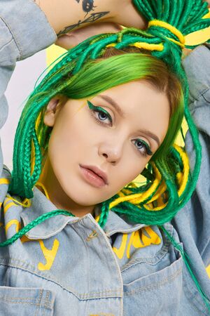 Portrait of a woman with creatively colored hair in green and yellow color. Colorful bright dreadlocks, beautiful modern makeupの写真素材