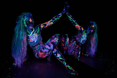 Art woman body art on the body dancing in ultraviolet light. Bright abstract drawings on the girl body neon color. Fashion and art womanの写真素材